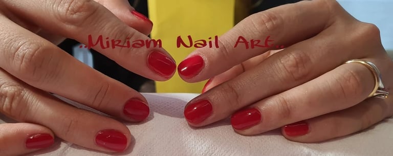 Person displaying manicured nails with glossy red polish against a yellow and white background