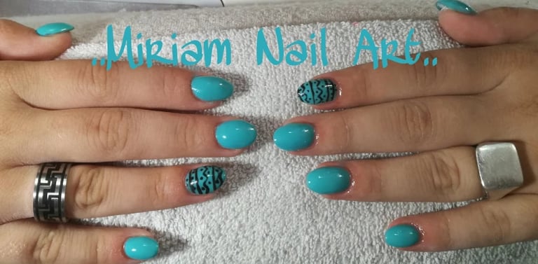 Two hands displaying turquoise nail polish with glittery accents and silver rings on a textured surface